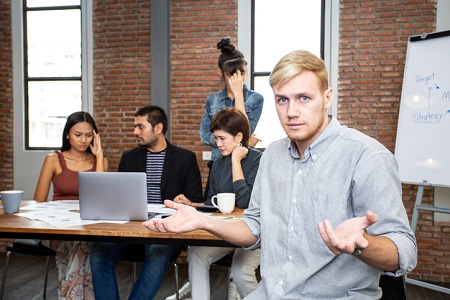 Man with hands raised in question with other team members looking frustrated. Credit: https://www.istockphoto.com/portfolio/Bavorndej