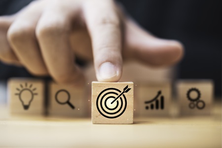 A man's finger pointing to a target image on wooden cube block. Credit: https://www.istockphoto.com/portfolio/DilokKlaisataporn