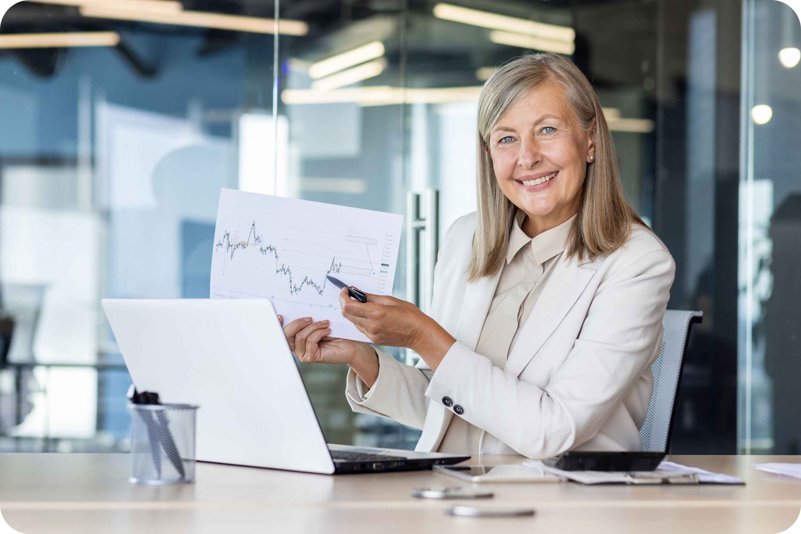 Senior business woman sitting at an office table, holding and showing a chart. CREDIT: https://www.istockphoto.com/portfolio/Voronaman