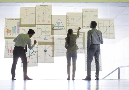 Business people working with charts and graphs on a glass wall. Credit: https://www.istockphoto.com/portfolio/koto